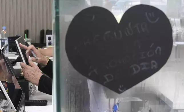 An employee rings up a customer inside a franchise of "Sabor Venezolano," one of 18 businesses owned by Wilmer Escaray which employ scores of Venezuelan immigrants with Temporary Protected Status (TPS) who are now potentially exposed to deportation, in Doral, Fla., Tuesday, May 20, 2025. (AP Photo/Rebecca Blackwell)