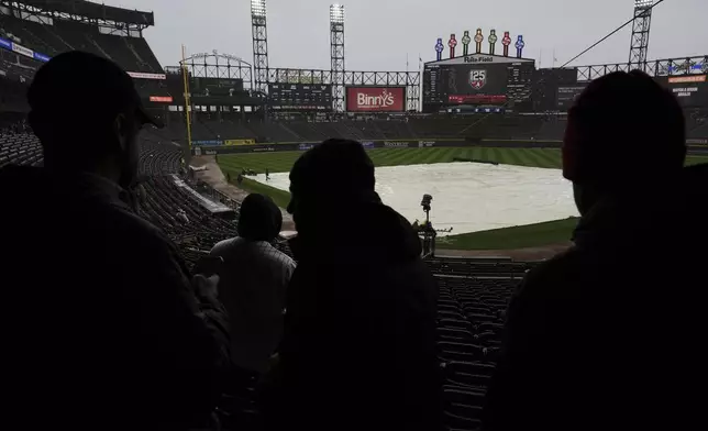 A tarp covers the infield as fans wait during a rain delay in the seventh inning of a baseball game between the Houston Astros and the Chicago White Sox in Chicago, Sunday, May 4, 2025. (AP Photo/Nam Y. Huh)