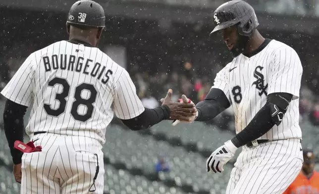 Chicago White Sox's Luis Robert Jr., right, celebrates with first base coach Jason Bourgeois (38) after hitting a one-run single during the sixth inning of a baseball game against the Houston Astros in Chicago, Sunday, May 4, 2025. (AP Photo/Nam Y. Huh)