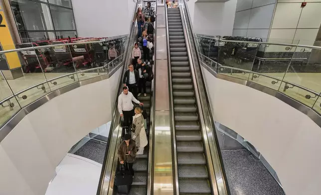 Passengers utilize an escalator at Newark Liberty International Airport, in New Jersey, Friday, May 23, 2025. (AP Photo/Richard Drew)