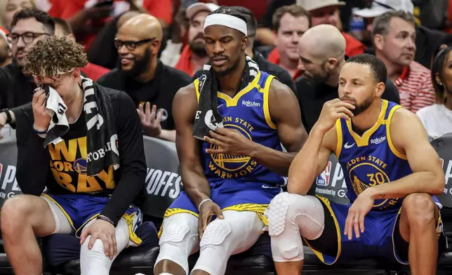 Brandin Podziemksi (2), Jimmy Butler (10) and Stephen Curry (30) react on the bench in the final seconds of the second half as the Golden State Warriors played the Houston Rockets in Game 5 of the First Round of the NBA Playoffs at Toyota Center in Houston, Texas on Wednesday, April 30, 2025. (Carlos Avila Gonzalez/San Francisco Chronicle via AP)
