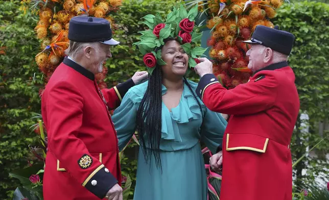 Chelsea Pensioners Jack McCabe, left, and Tony Manley, right, look at the hat worn by Claire Myers-Lamptey designed by Mathew Eluwande for Nature Recovery, for communities to embrace re-wilding at the RHS Chelsea Flower Show in London, Monday, May 19, 2025. (AP Photo/Kirsty Wigglesworth)