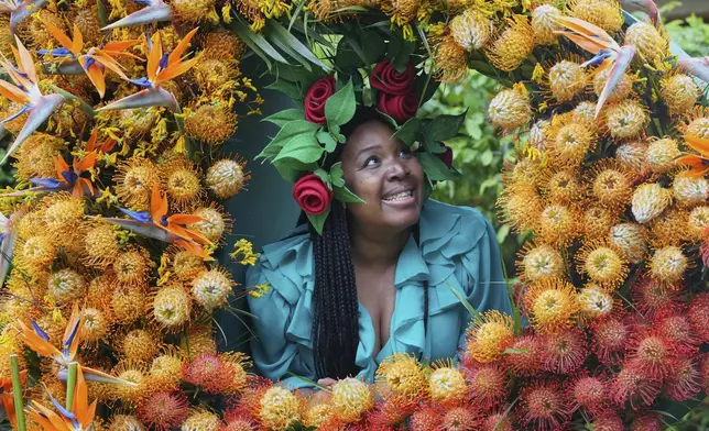 Claire Myers-Lamptey wears a hat by Mathew Eluwande for Nature Recovery, for communities to embrace re-wilding as she looks through a display at the RHS Chelsea Flower Show in London, Monday, May 19, 2025. (AP Photo/Kirsty Wigglesworth)