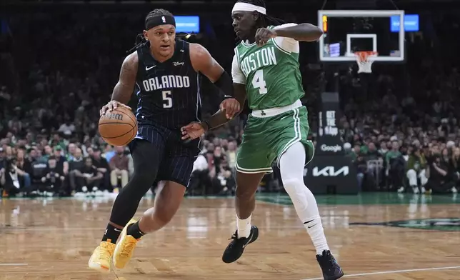 Orlando Magic forward Paolo Banchero (5) drives to the basket against Boston Celtics guard Jrue Holiday (4) during the first half in game 2 of a first-round NBA playoff basketball series, Wednesday, April 23, 2025, in Boston. (AP Photo/Charles Krupa)