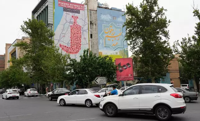 Vehicles drive past an anti-Israel banner showing numerous locations in Israel as a Yemeni dagger (jambiya) with writing in Farsi reading: "All targets are within range, Yemeni missiles for now!", and in Hebrew "All targets are within reach, we will choose", at the Felestin (Palestine) Sq. in downtown Tehran, Iran, Monday, May 5, 2025. (AP Photo/Vahid Salemi)