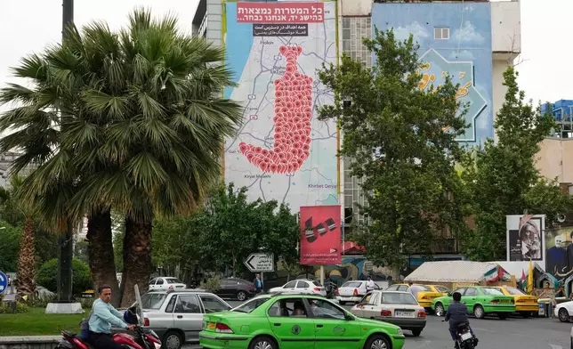 Vehicles and motorcycles drive past an anti-Israel banner showing numerous locations in Israel as a Yemeni dagger (jambiya) with writing in Farsi reading: "All targets are within range, Yemeni missiles for now!", and in Hebrew "All targets are within reach, we will choose", at the Felestin (Palestine) Sq. in downtown Tehran, Iran, Monday, May 5, 2025. (AP Photo/Vahid Salemi)