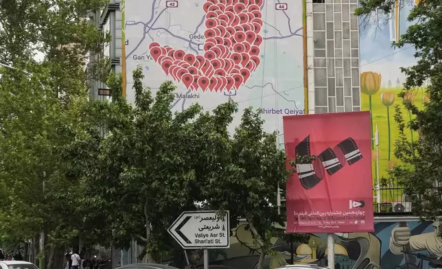 Motorcycles drive past an anti-Israel banner showing numerous locations in Israel as a Yemeni dagger (jambiya) with writing in Farsi reading: "All targets are within range, Yemeni missiles for now!", and in Hebrew "All targets are within reach, we will choose", at the Felestin (Palestine) Sq. in downtown Tehran, Iran, Monday, May 5, 2025. (AP Photo/Vahid Salemi)
