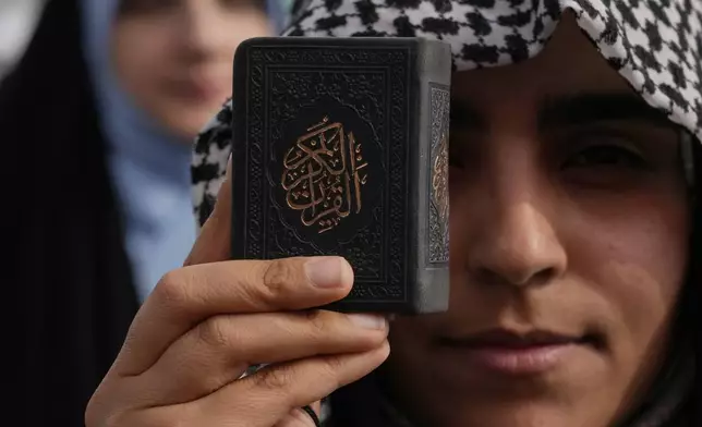 A demonstrator holds a copy of Islam's holy book, Quran, during a pro-Palestinian gathering in Tehran, Iran, Friday, May 2, 2025. (AP Photo/Vahid Salemi)
