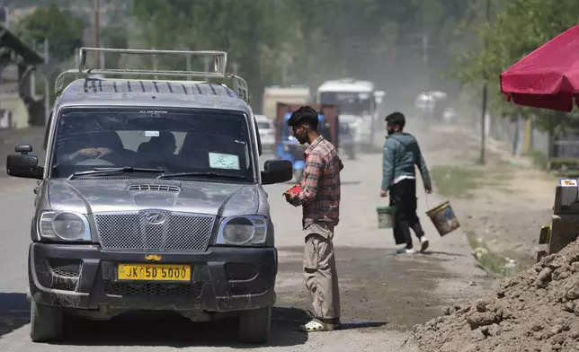 A Kashmiri man sells cherry to passersby and travelers on the Srinagar-Muzaffarabad highway, after India and Pakistan reported no incidents of firing overnight, in Pattan in Indian controlled Kashmir Monday, May 12, 2025. (AP Photo/Mukhtar Khan)