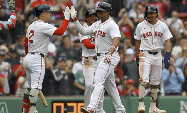Boston Red Sox's Rafael Devers, center front, exchanges a high-five with Alex Bregman, left, as he celebrates after scoring on his grand slam in the third inning of a baseball game against the Atlanta Braves, Sunday, May 18, 2025, in Boston. (AP Photo/Steven Senne)