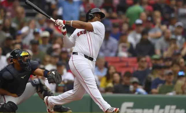 Boston Red Sox's Rafael Devers, right, follows through on his swing after hitting a grand slam in front of Atlanta Braves catcher Drake Baldwin, left, in the third inning of a baseball game, Sunday, May 18, 2025, in Boston. (AP Photo/Steven Senne)