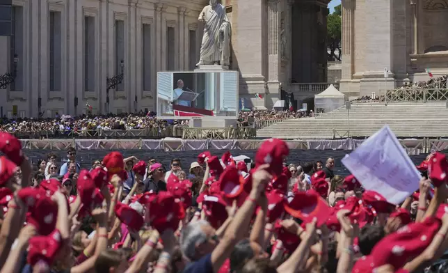 People watch Pope Leo XIV on a giant screen as he delivers his blessing from the window in St. Peter's Square for the Regina Caeli noon prayer, Sunday, May 25, 2025. (AP Photo/Andrew Medichini)