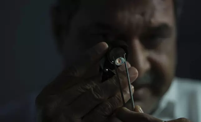 A worker inspects a polished diamond at Shree Ramkrishna Exports in Surat, India, on April 14, 2025. (AP Photo/Ajit Solanki)