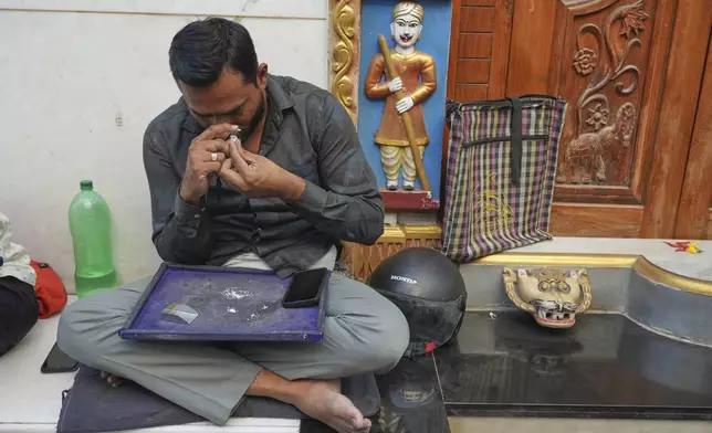 A trader inspects a diamond as he sits on a pavement at a market in Surat, India, on April 14, 2025. (AP Photo/Ajit Solanki)