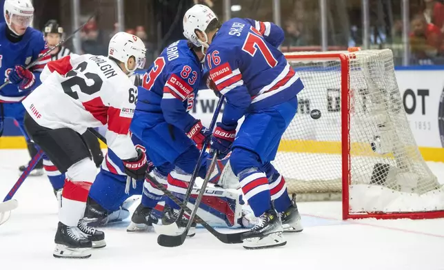 Switzerland Denis Malgin, left, challenges U.S. Conor Garland and Brady Skjei, right, during the IIHF Ice Hockey World Championship group B match between the U.S. and Switzerland in Herning, Denmark, Monday, May 12, 2025. (Bo Amstrup/Ritzau Scanpix via AP)