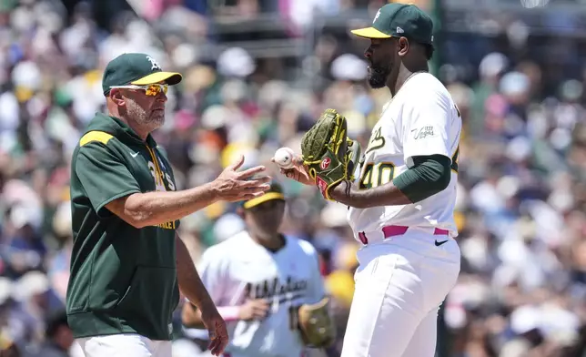 Athletics pitcher Luis Severino, right, hands the ball over to manager Mark Kotsay, left, was he exits during the fifth inning of a baseball game against the New York Yankees, Sunday, May 11, 2025, in West Sacramento, Calif. (AP Photo/Godofredo A. Vásquez)