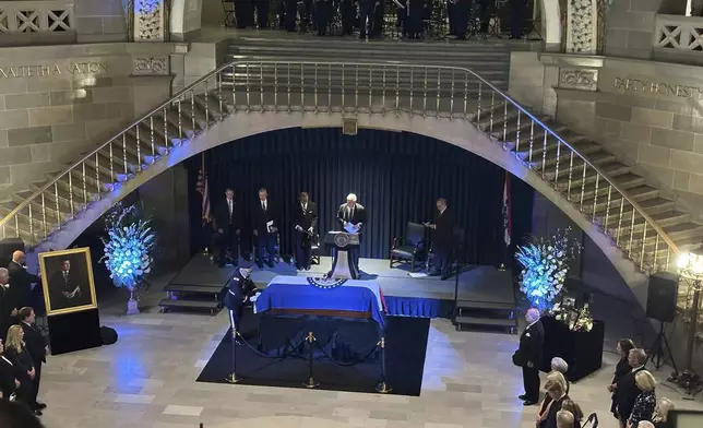 An officer stands by the casket of former Missouri Gov. and U.S. Sen. Christopher "Kit" Bond as former U.S. Sen. John Danforth prepares to speak at a memorial service for Bond on Tuesday, May 20, 2025, in the Missouri Capitol in Jefferson City, Mo. (AP Photo/David A. Lieb)