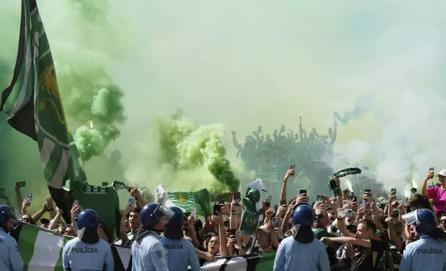Police keep an eye on Sporting supporters outside the stadium ahead of the Portuguese league last round soccer match between Sporting CP and Vitoria SC at the Alvalade stadium in Lisbon, Saturday, May 17, 2025. (AP Photo/Ana Brigida)
