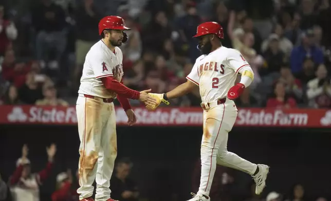 Los Angeles Angels' Luis Rengifo (2) and Travis d'Arnaud (25) celebrate after they scored on a single by Kyren Paris during the sixth inning of a baseball game against the Detroit Tigers Saturday, May 3, 2025, in Anaheim, Calif. (AP Photo/Jae C. Hong)