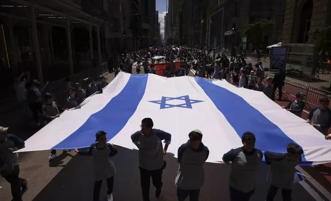The Israeli flag is carried down Fifth Avenue during the Israel Day Parade, Sunday, May 18, 2025, in New York. (AP Photo/Yuki Iwamura)