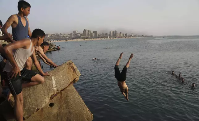 Palestinians jump into the water of the Mediterranean Sea to cool down during a heat wave in Gaza City, Saturday, May 17, 2025. (AP Photo/Jehad Alshrafi)