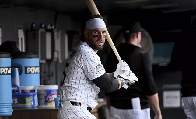 Colorado Rockies' Nick Martini (35) practices his swing in the dugout during the second inning of a baseball game against the Philadelphia Phillies Wednesday, May 21, 2025, in Denver. (AP Photo/Geneva Heffernan)