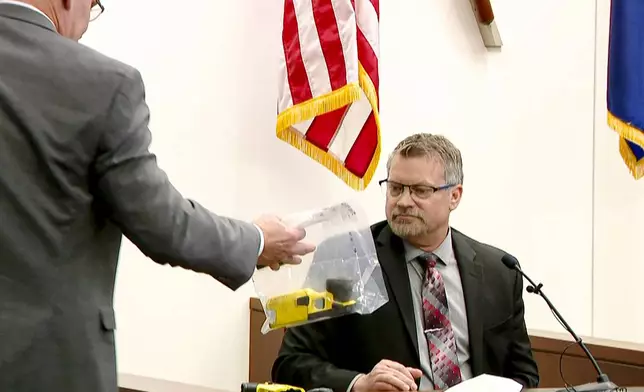 Kent County Prosecutor Chris Becker shows Bryan Chiles, senior manager of Axon Forensics, the Taser7 used by former Grand Rapids Police officer Christopher Schurr on Patrick Lyoya during the second day of trial at the Kent County Courthouse in Grand Rapids, Mich. on Tuesday, April 29, 2025. (WOOD-TV via AP, Pool)