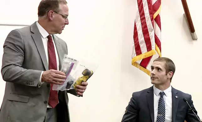 In this image taken from video from WOOD-TV, Kent County Prosecutor shows Aaron Tubergen, a detective sergeant with the Michigan State Police, the Taser of former Grand Rapids Police officer Christopher Schurr, who is charged in the 2022 killing of a Black motorist, Patrick Lyoya, as he testifies during the first day of Schurr's murder trial at the Kent County Courthouse in Grand Rapids, Mich., Monday, April 28, 2025. (WOOD-TV, Pool Photo/Kalamazoo Gazette via AP)