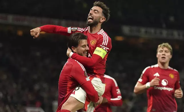 Manchester United's Mason Mount, left, celebrates with Bruno Fernandes after scoring their first goal of the game during the Europa League semifinal second leg soccer match between Manchester United and Athletic Bilbao in Manchester, Britain, Thursday, May 8, 2025. (Martin Rickett/PA via AP)