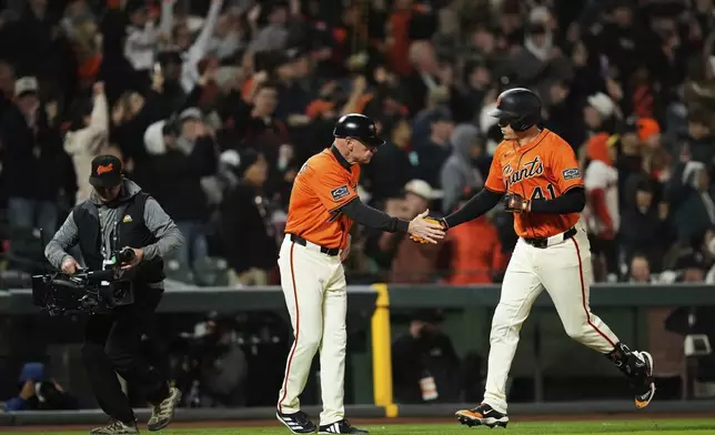 San Francisco Giants' Wilmer Flores, right, celebrates with third base coach Matt Williams after hitting a three-run home run during the sixth inning of a baseball game against the Athletics, Friday, May 16, 2025, in San Francisco. (AP Photo/Godofredo A. Vásquez)