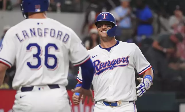 Texas Rangers' Josh Jung, right, smiles after hitting a home run during the first inning of a baseball game against the Colorado Rockies, Tuesday, May 13, 2025, in Arlington, Texas. (AP Photo/LM Otero)