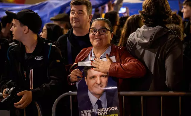 A supporter of presidential candidate Nicusor Dan holds an electoral poster after he won the second round of the country's presidential election redo in Bucharest, Romania, early Monday, May 19, 2025. (AP Photo/Andreea Alexandru)