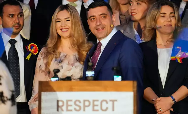 Presidential candidate George Simion, front right, smiles with his wife Ilinca during a press conference after polls closed for the second round of the country's presidential election redo in Bucharest, Romania, Sunday, May 18, 2025. (AP Photo/Vadim Ghirda)