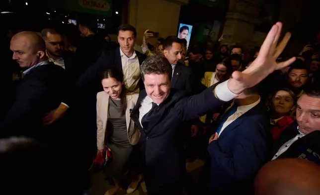 Presidential candidate Nicusor Dan, center, waves to supporters next to his partner Mirabela Gradinaru after winning the second round of the country's presidential election redo in Bucharest, Romania, early Monday, May 19, 2025. (AP Photo/ Alexandru Dobre)