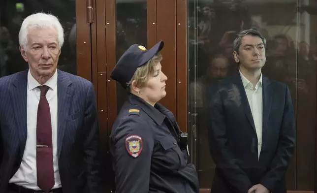 Grigory Melkonyants, right, co-chair of Russia's leading independent election monitoring group Golos who faces up to 5 years in prison, looks at the media standing in a cage in a courtroom prior to a hearing as Lawyer Mikhail Biryukov, stands near in Basmanny district court in Moscow, Russia, Wednesday, May 14, 2025. (AP Photo/Alexander Zemlianichenko)