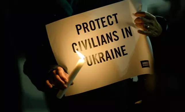 FILE - People hold candles and signs during a vigil organized by Amnesty International in solidarity with the Ukrainian people, in Lisbon, Feb. 28, 2022. (AP Photo/Armando Franca, File)