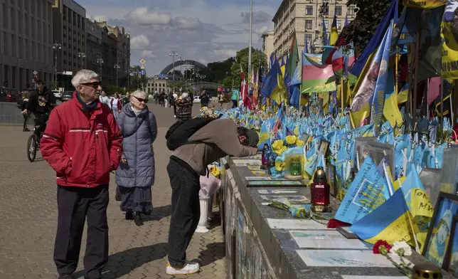 People pay their respect at the memorial to the fallen Ukrainian soldiers on Independence Square in Kyiv, Ukraine, Monday, May 19, 2025. (AP Photo/Efrem Lukatsky)