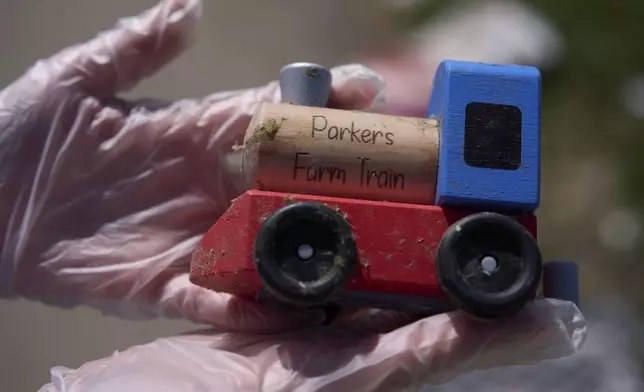 A resident holds her grandson's tory train as she looks for salvageable items of her daughter's destroyed home, Sunday, May 18, 2025, in London, Ky., after a severe storm passed through the area. (AP Photo/Carolyn Kaster)