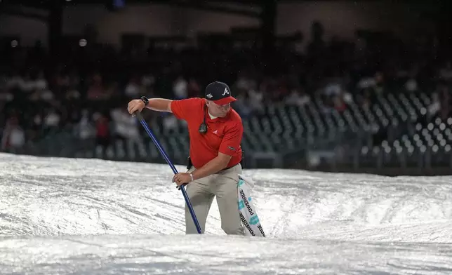 Grounds crew work during a rain delay in the ninth inning of a baseball game between the Atlanta Braves and the Los Angeles Dodgers, Friday, May 2, 2025, in Atlanta. (AP Photo/Mike Stewart)