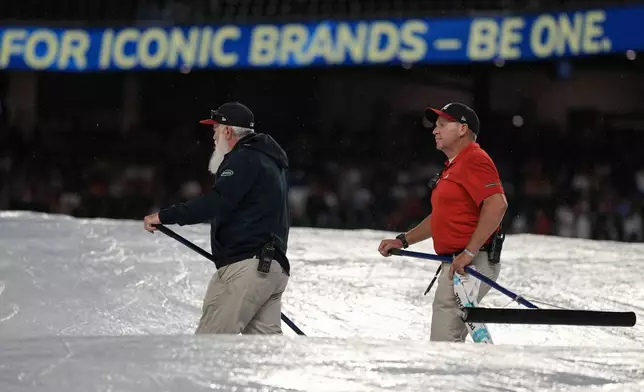 Grounds crew work during a rain delay in the ninth inning of a baseball game between the Atlanta Braves and the Los Angeles Dodgers, Friday, May 2, 2025, in Atlanta. (AP Photo/Mike Stewart)