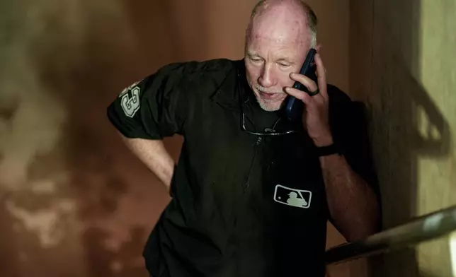 Umpire Lance Barksdale speaks on the phone during a rain delay in the ninth inning of a baseball game between the Atlanta Braves and the Los Angeles Dodgers, Friday, May 2, 2025, in Atlanta. (AP Photo/Mike Stewart)