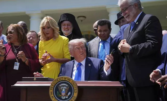 President Donald Trump hands pens used to sign an executive order establishing the Religious Liberty Commission, to religious leaders during a National Day of Prayer event in the Rose Garden of the White House, Thursday, May 1, 2025, in Washington. (AP Photo/Evan Vucci)