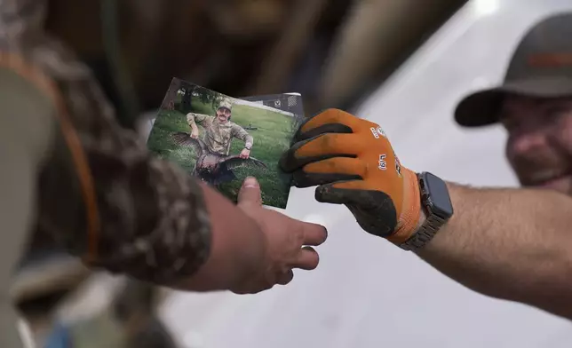 Family friend Melvin Brock, right, finds a photo as he sifts through what is left of Wilson's destroyed home, Sunday, May 18, 2025, in London, Ky., after a severe storm passed through the area. (AP Photo/Carolyn Kaster)