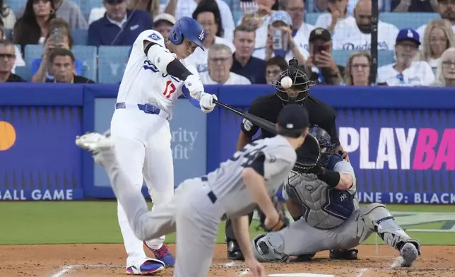 Los Angeles Dodgers' Shohei Ohtani, left, hits a solo home run as New York Yankees starting pitcher Max Fried, center, and catcher Austin Wells watch during the first inning of a baseball game Friday, May 30, 2025, in Los Angeles. (AP Photo/Mark J. Terrill)