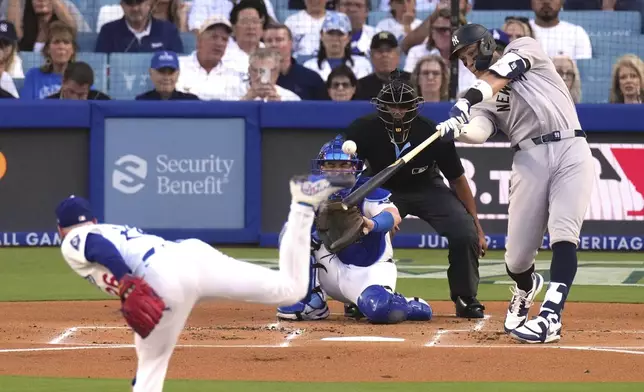 New York Yankees' Aaron Judge, right, hits a solo home run as Los Angeles Dodgers starting pitcher Tony Gonsolin, left, and catcher Will Smith watch during the first inning of a baseball game Friday, May 30, 2025, in Los Angeles. (AP Photo/Mark J. Terrill)