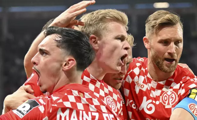 Mainz's Jonathan Burkhardt, center, celebrates with teammates after scoring a goal, during the German Bundesliga soccer match between FSV Mainz 05 and Eintracht Frankfurt, at Mewa Arena, in Mainz, Germany, Sunday, May 4, 2025. (Torsten Silz/dpa via AP)