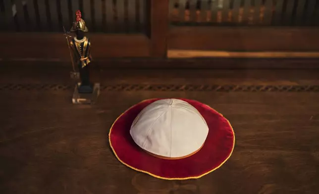 A Pope skullcap lays in the display window of the Gammarelli ecclesiastic clothes tailor shop in Rome, Wednesday, April 30, 2025. (AP Photo/Francisco Seco)