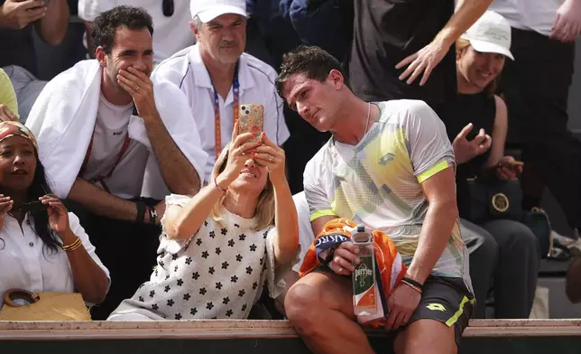 Argentina's Federico Gomez takes a selfie with a fan as he plays Britain's Cameron Norrie during their second round match of the French Tennis Open, at the Roland-Garros stadium, in Paris, Thursday, May 29, 2025. (AP Photo/Lindsey Wasson)