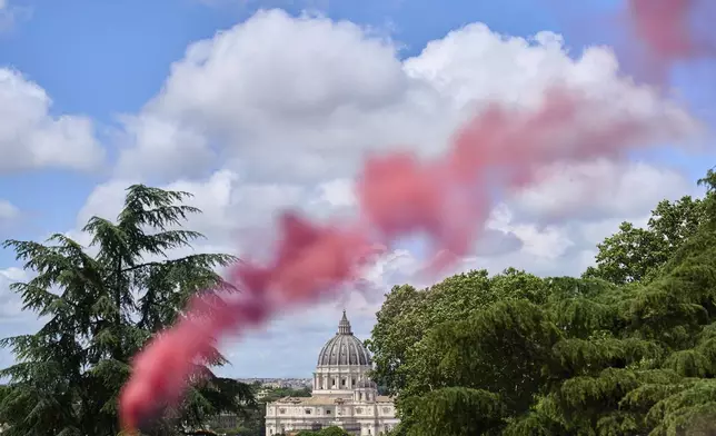 FILE - Pink smoke rises in front of St. Peter's Basilica during a protest by the Women's Ordination Conference calling for full equality for women in the Catholic Church on the first day of the conclave to elect the 267th pope in Rome on Wednesday, May 7, 2025. (AP Photo/Bernat Armangue, File)
