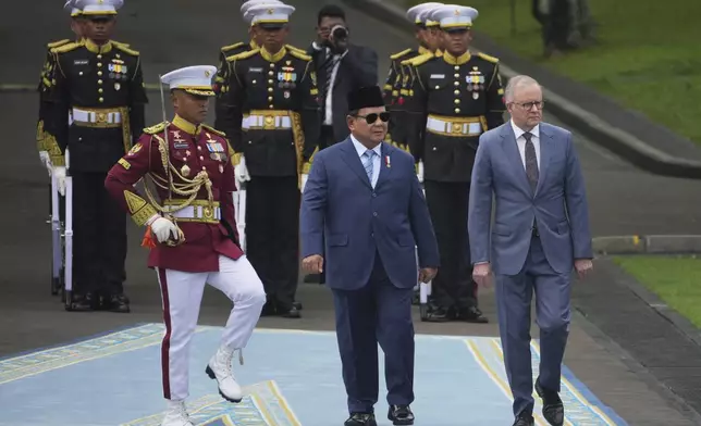 Australian Prime Minister Anthony Albanese, right, walks with Indonesian President Prabowo Subianto, center, while inspecting a honor guard before their meeting at Merdeka Palace in Jakarta, Indonesia, Thursday, May 15, 2025. (AP Photo/Dita Alangkara)